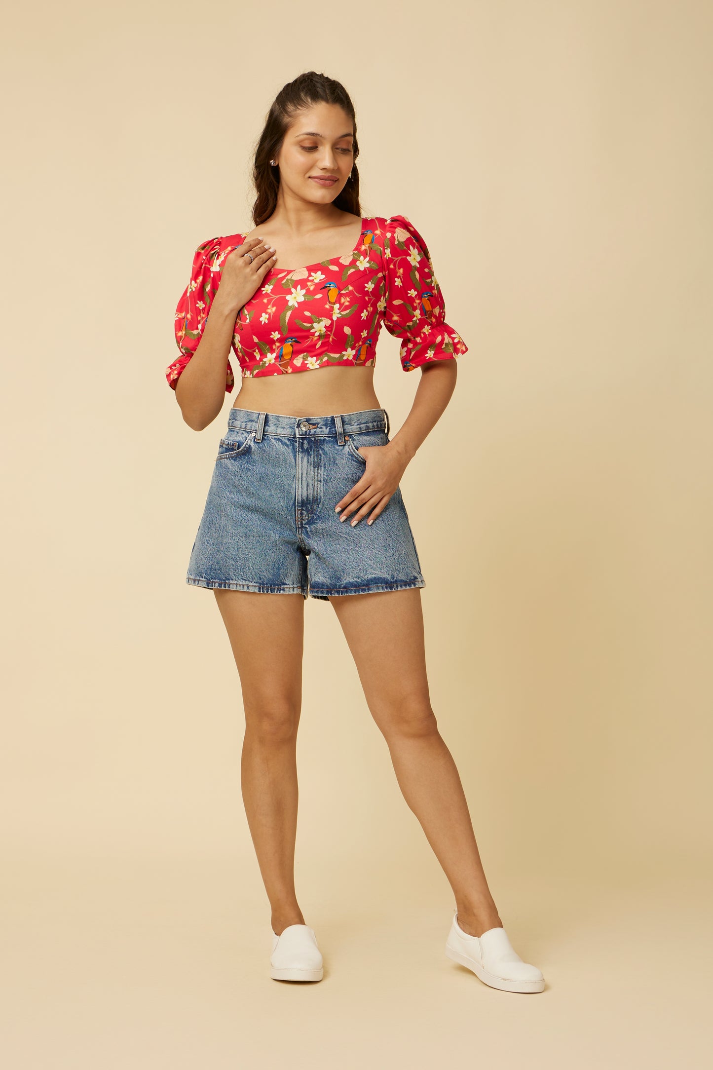Model poses with hand on hip in the Crimson Summery Crop Top, showcasing the full charm of the floral pattern, complemented by the striking sweetheart neckline and contemporary puff sleeves.