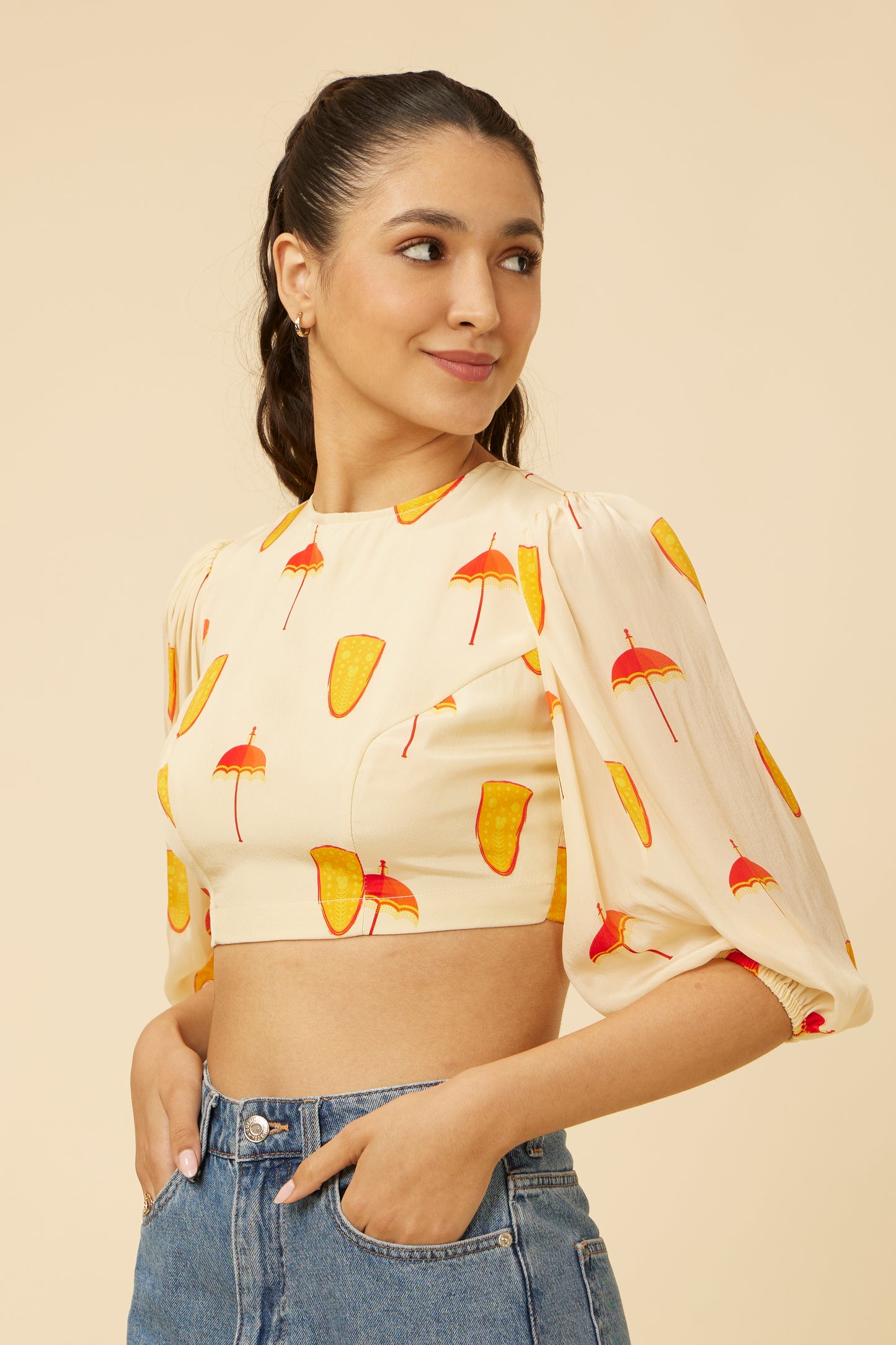 Model in Spree in Ivory Crop Top with a bandh neck and balloon sleeves featuring vibrant Thrissur Pooram motifs, paired with high-waisted denim