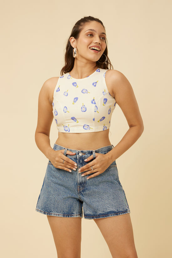 Cheerful model with hands on waist wearing the Hypsway Blue Pea Crop Top, exuding confidence in the light-hued top with distinct blue pea prints, paired with stylish denim shorts, ideal for a fresh, everyday summer look.