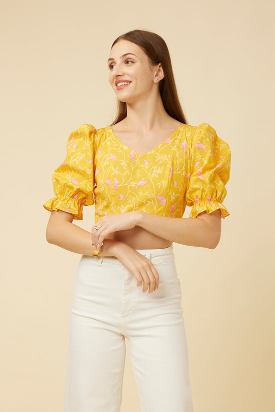 Model smiling in Peela Sunshine Crop Top with voluminous sleeves and V-neckline, exuding style and cheer against a soft beige background