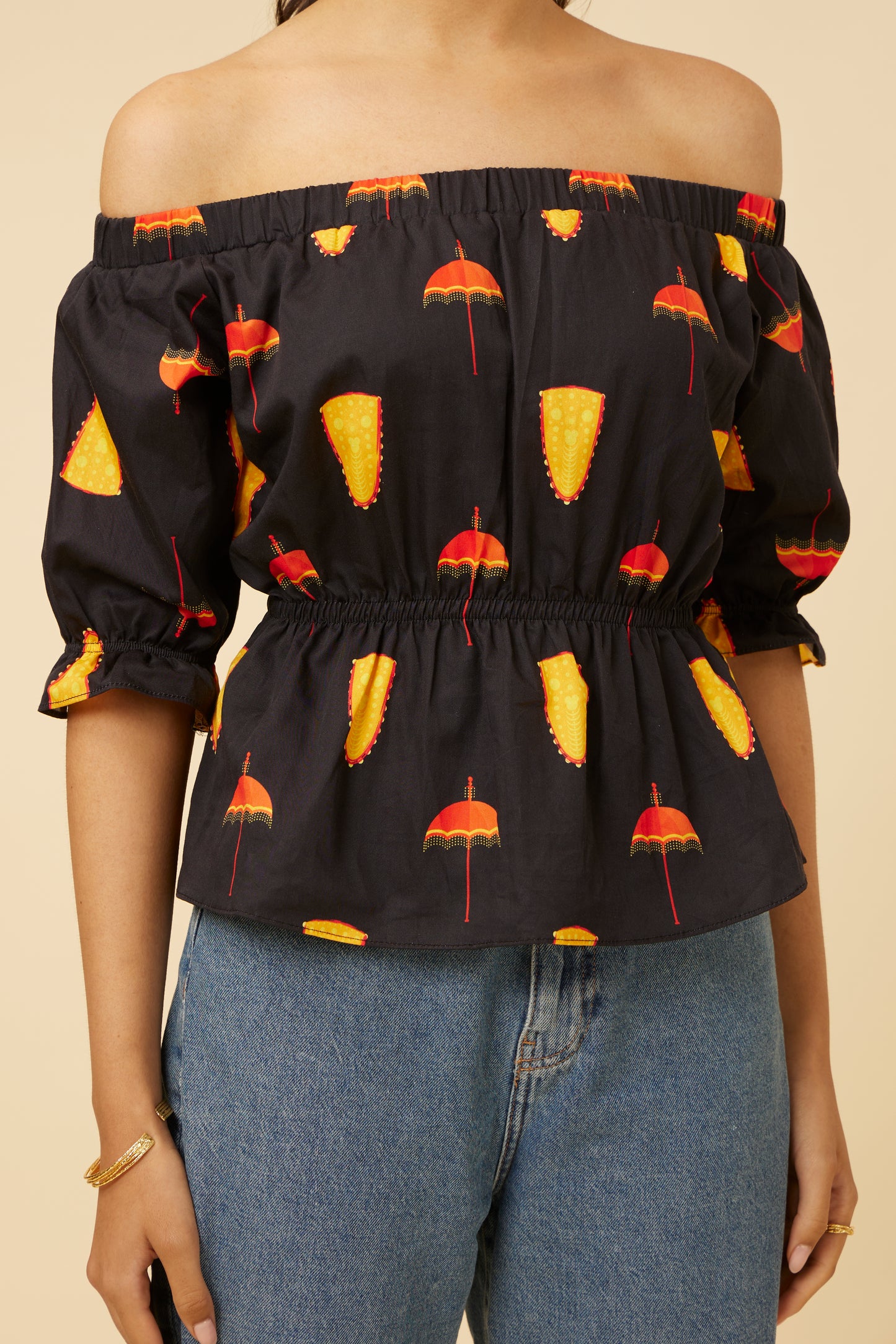 Close-up of the back of the Spree in Black Off-Shoulder Top, emphasizing the elastic cinched waist and balloon sleeve detail with cultural motifs