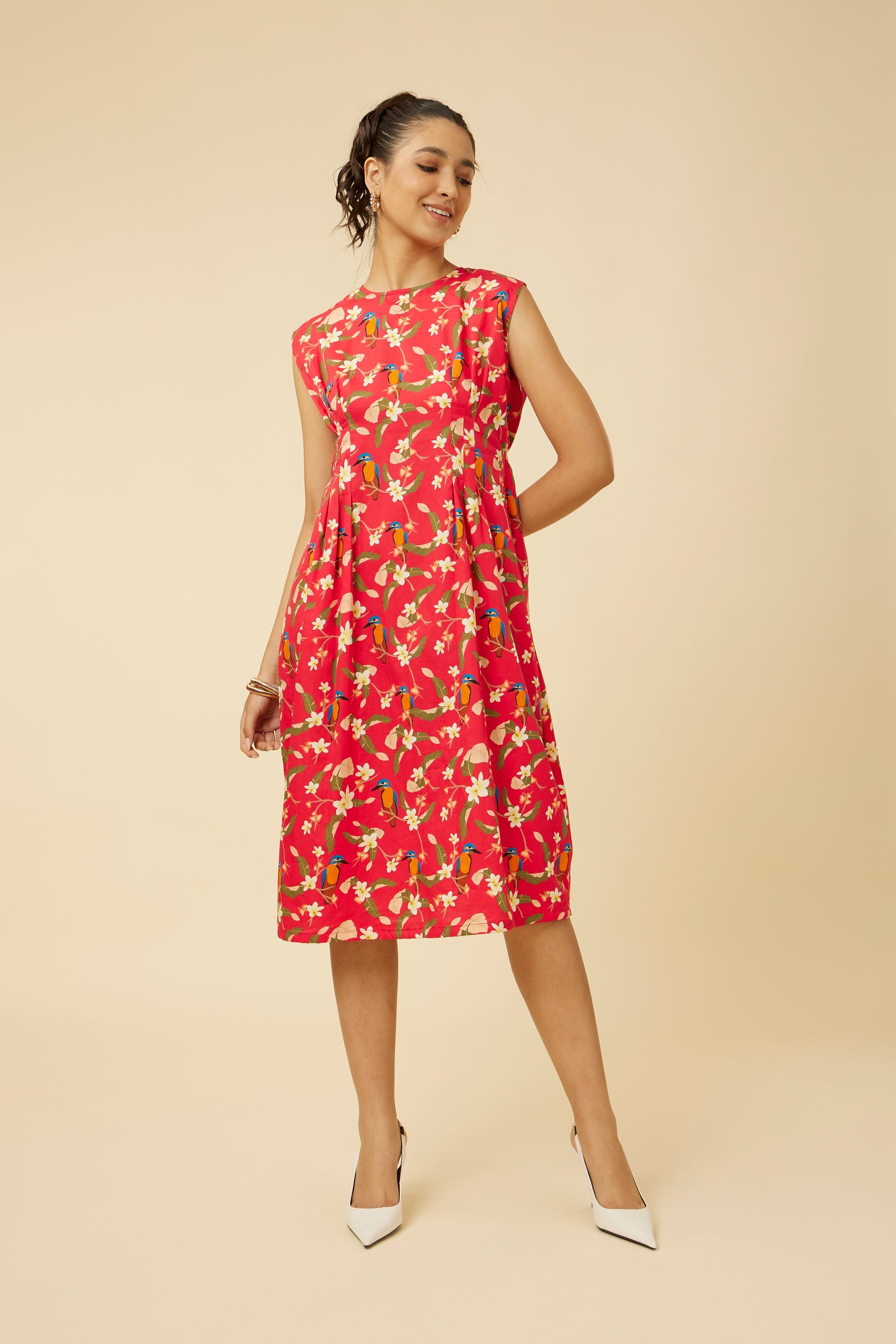 Elegant three-quarter view of a sleeveless Crimson Summery Dress with kingfisher, plumeria, leaves, and roseapple prints, showcasing the A-line silhouette and front tucks.
