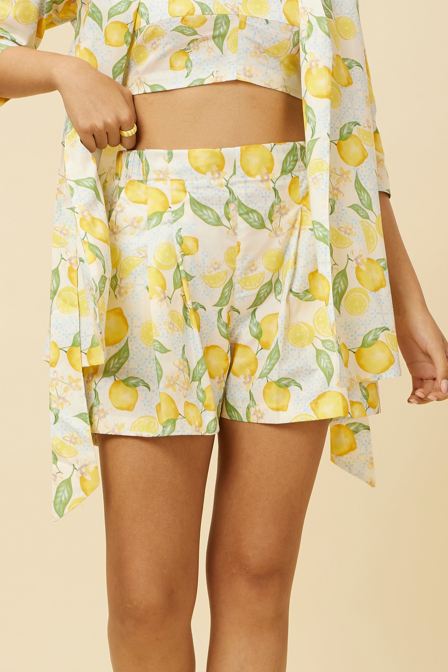 Detailed close-up of the Citrus Dream Shorts featuring an elastic back for comfort, a stylish front patch belt, and a playful lemon tile print on a white base, perfect for a vibrant summer wardrobe addition.