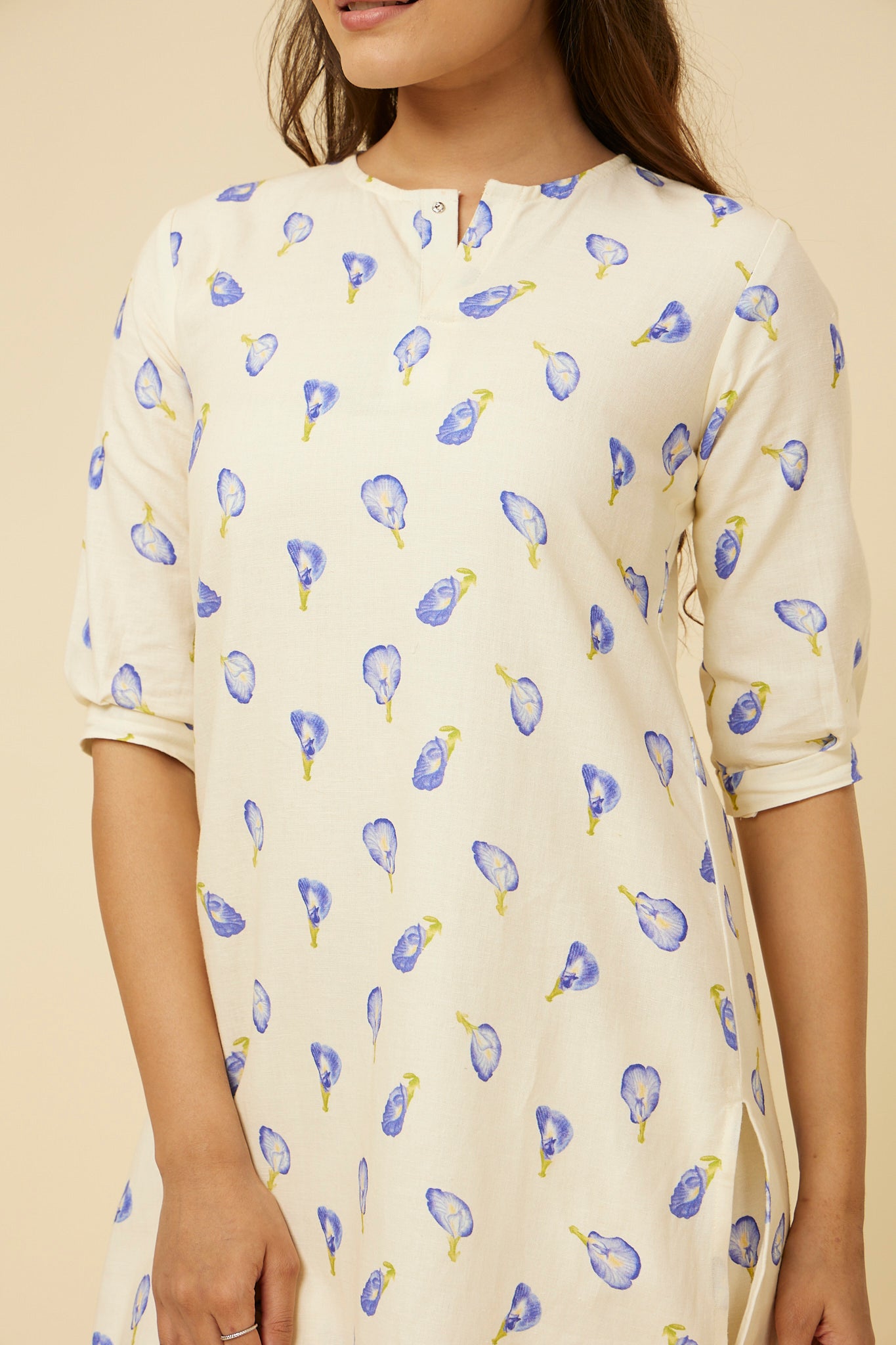Detailed view of the Blue Pea Kurta's fabric and design, showcasing the subtle front slit and closed neckline, with the 3/4 long sleeves enhancing the sleek look, all in a delicate blue pea floral print on white.