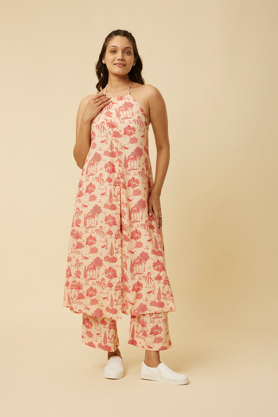 Front view of a Jaipur Rani dress in A-line silhouette with center tie and three-quarter sleeves, featuring a pink and red traditional print on an off-white background, model standing against a neutral backdrop