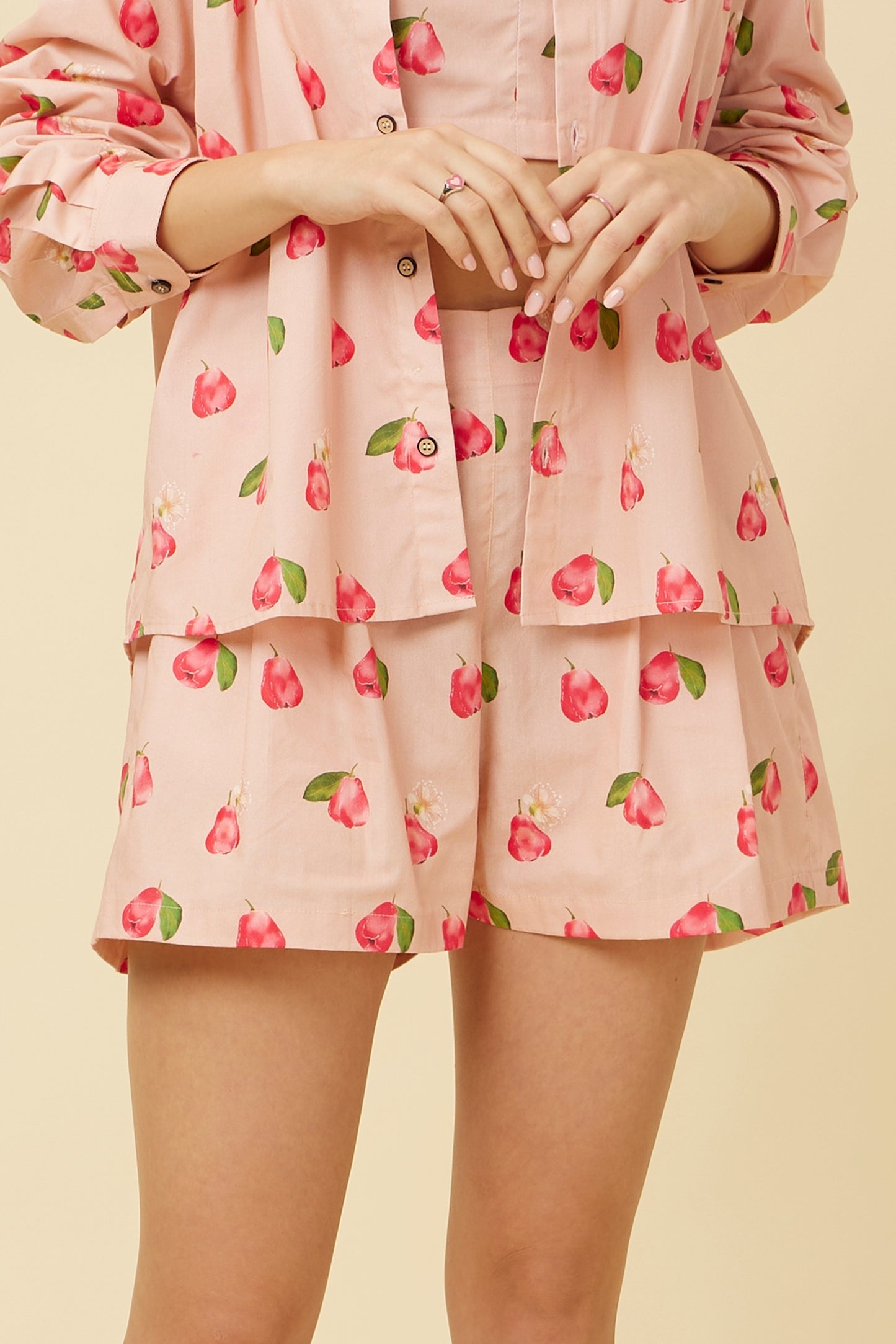Close-up of Rose Apple Shorts with elastic back and front patch belt, featuring a comfort fit and side pockets, adorned with whimsical rose apple print on pink fabric