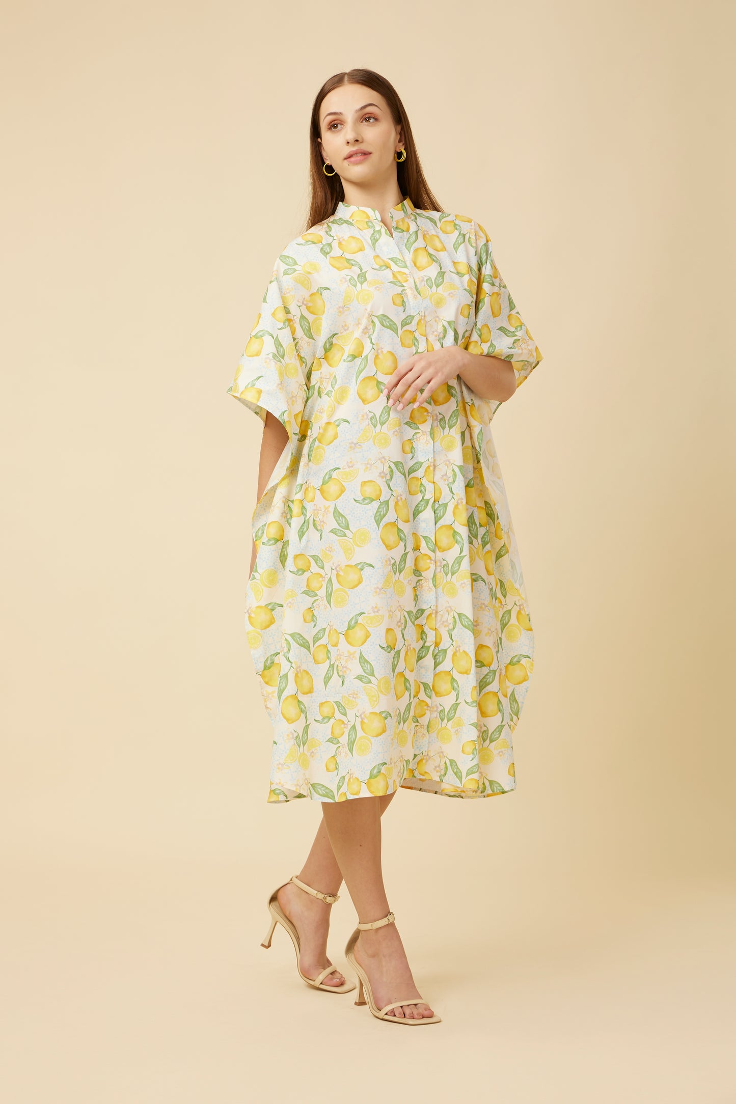 Model wears the Citrus Dream Shirt Dress Kaftan, draped in a fresh lemon tile print. The dress's collar neckline and relaxed fit marry casual comfort with effortless style, making it perfect for a summery vibe.