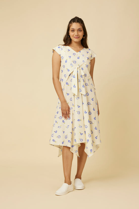Elegant model in a Blue Pea Dress, featuring delicate blue pea florals on a crisp white base, with a unique V-neck design and center front ties, paired with white sneakers, evoking a fresh, summery charm.