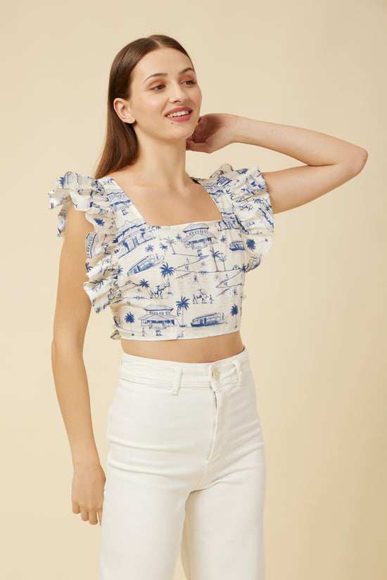 Model in a Homeland Frill Crop Top with a square front neckline and frill shoulder accents, paired with white high-waisted pants for a modern traditional look