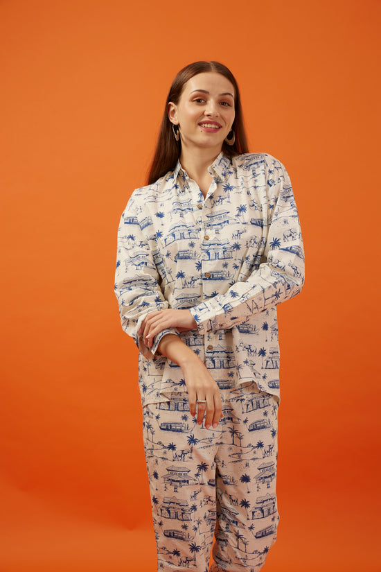 Sophisticated young woman modeling a Hypsway printed shirt and matching trousers set, featuring classic Indian architectural motifs on an ivory background, creating an effortlessly stylish and cohesive ensemble for the contemporary professional woman.